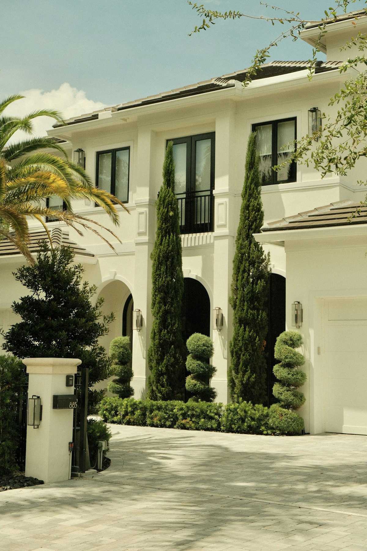 A gated Atherton estate with a long paver driveway, cypress trees and manicured landscaping