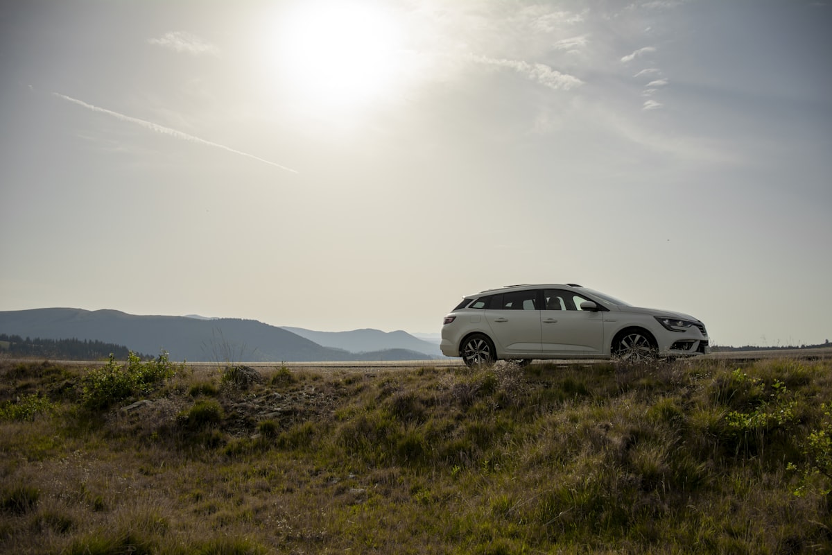 A wagon parked on a grassy hillside overlook with mountains in the distance, packed and ready for a road trip out of the Bay Area