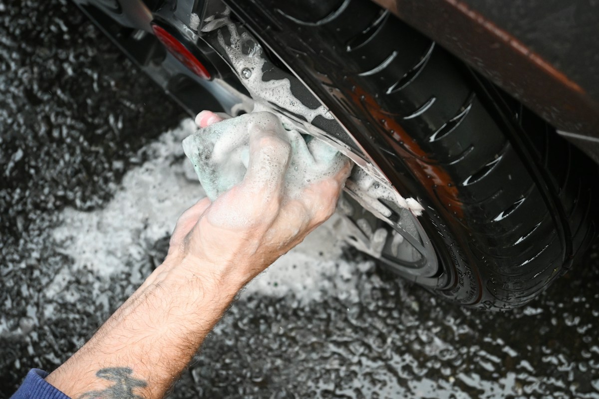 Hand-washing soap suds worked into a wheel well and lower panel near the exhaust