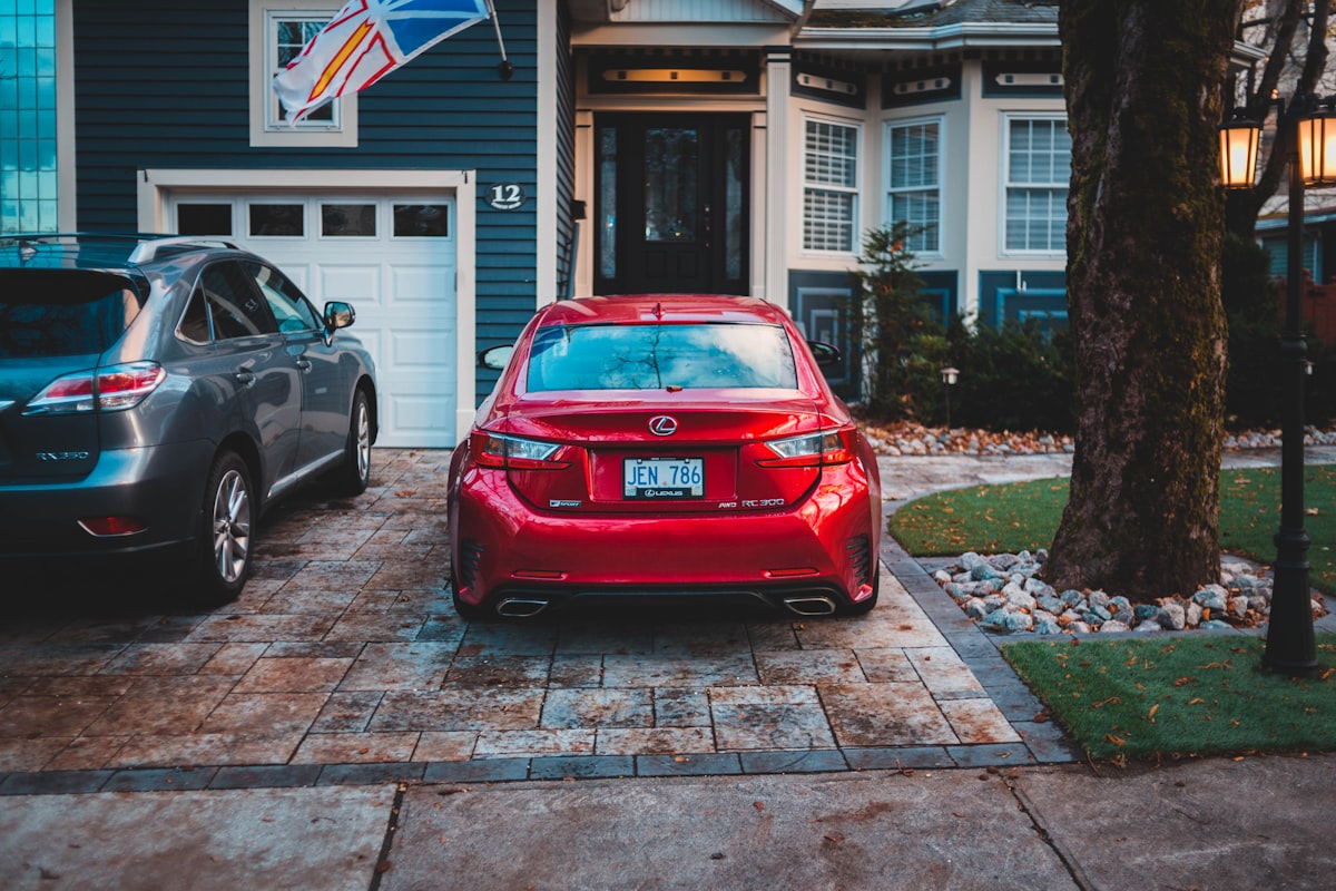 Two cars parked in a residential driveway in front of a home