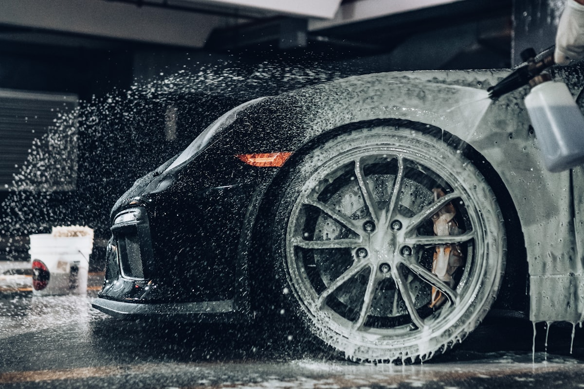 Foam and water rinsing bug splatter and road grime off a car's front end and wheel