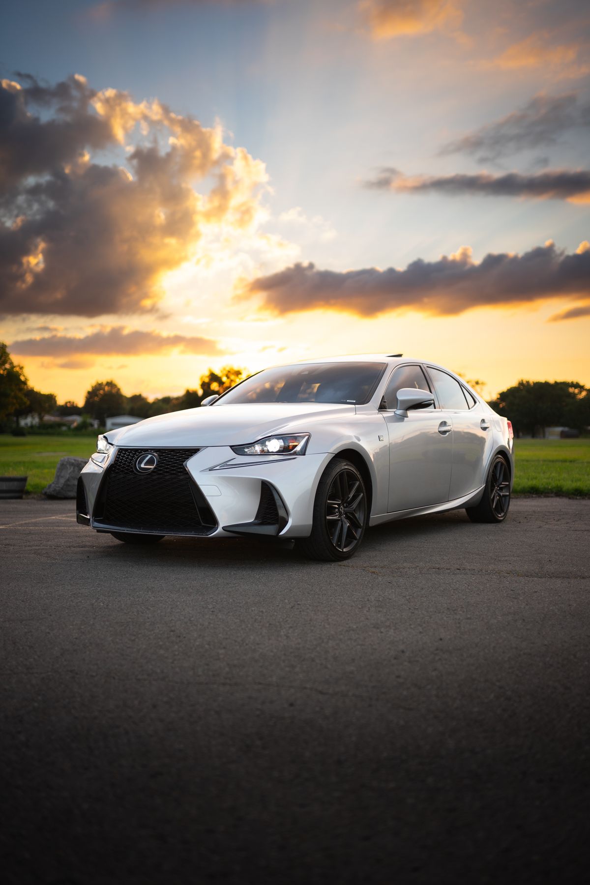 A silver Lexus IS F-Sport with a clean spindle grille and glossy paint at sunset.
