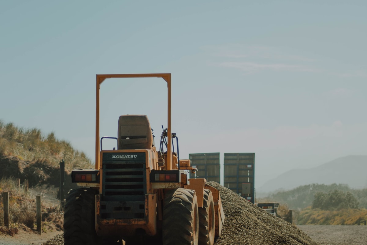 Construction equipment working a dirt and gravel site under a hazy sky, similar to the active grading around Milpitas's Great Mall BART corridor