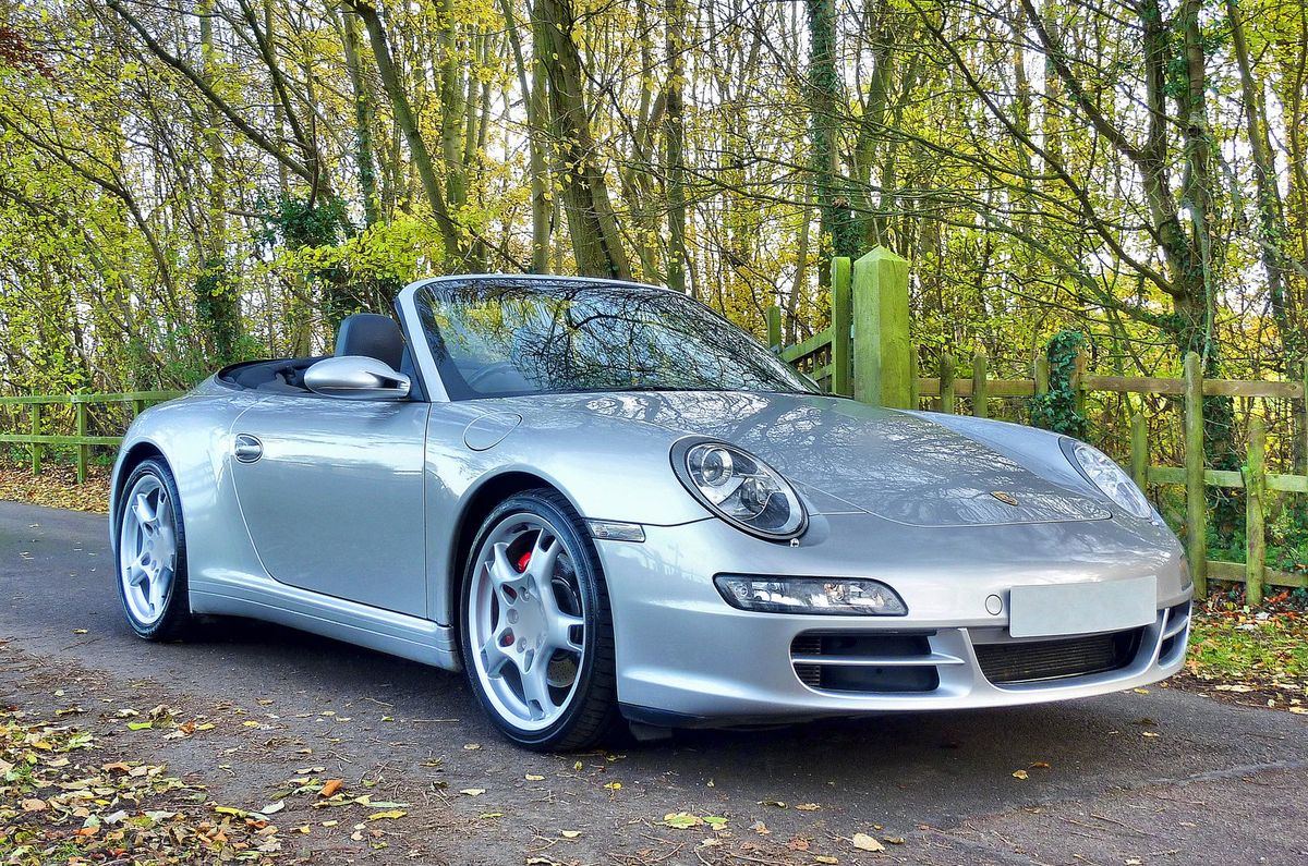 A silver Porsche 911 convertible with clean, swirl-free paintwork parked on a country lane.