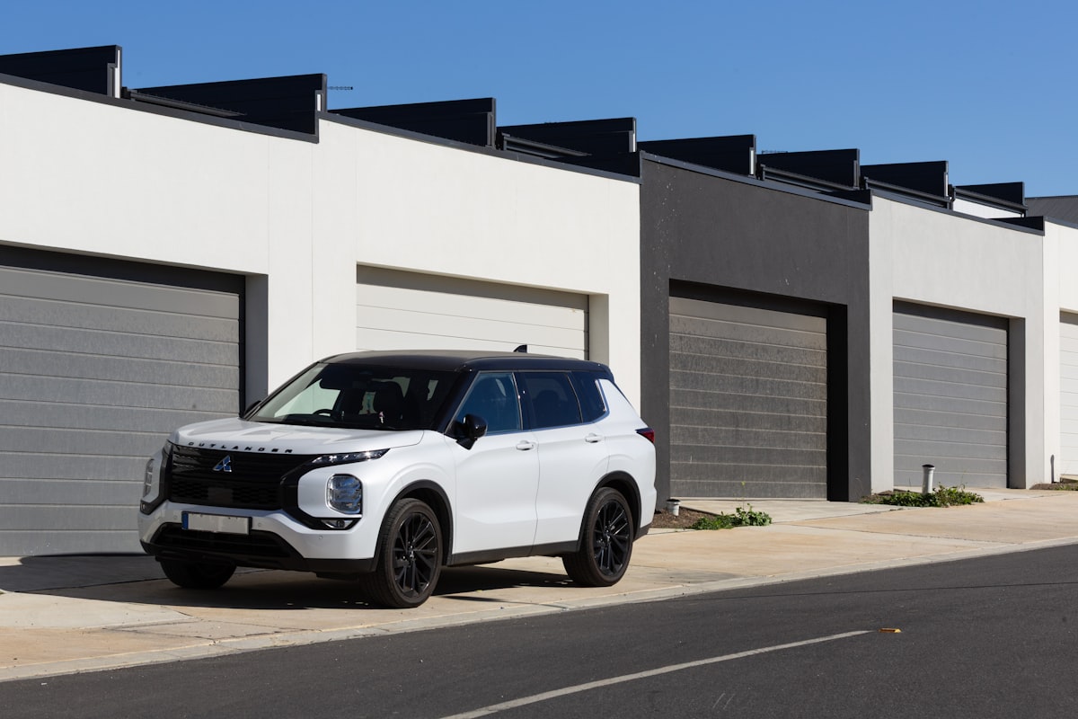 An SUV parked in front of a row of modern townhome garages