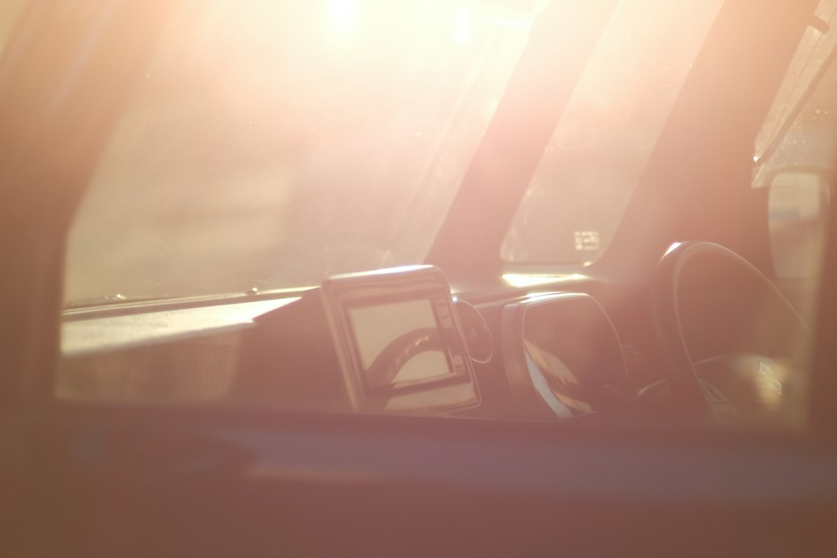 Bright sunlight flaring through a car windshield directly onto the dashboard and center console